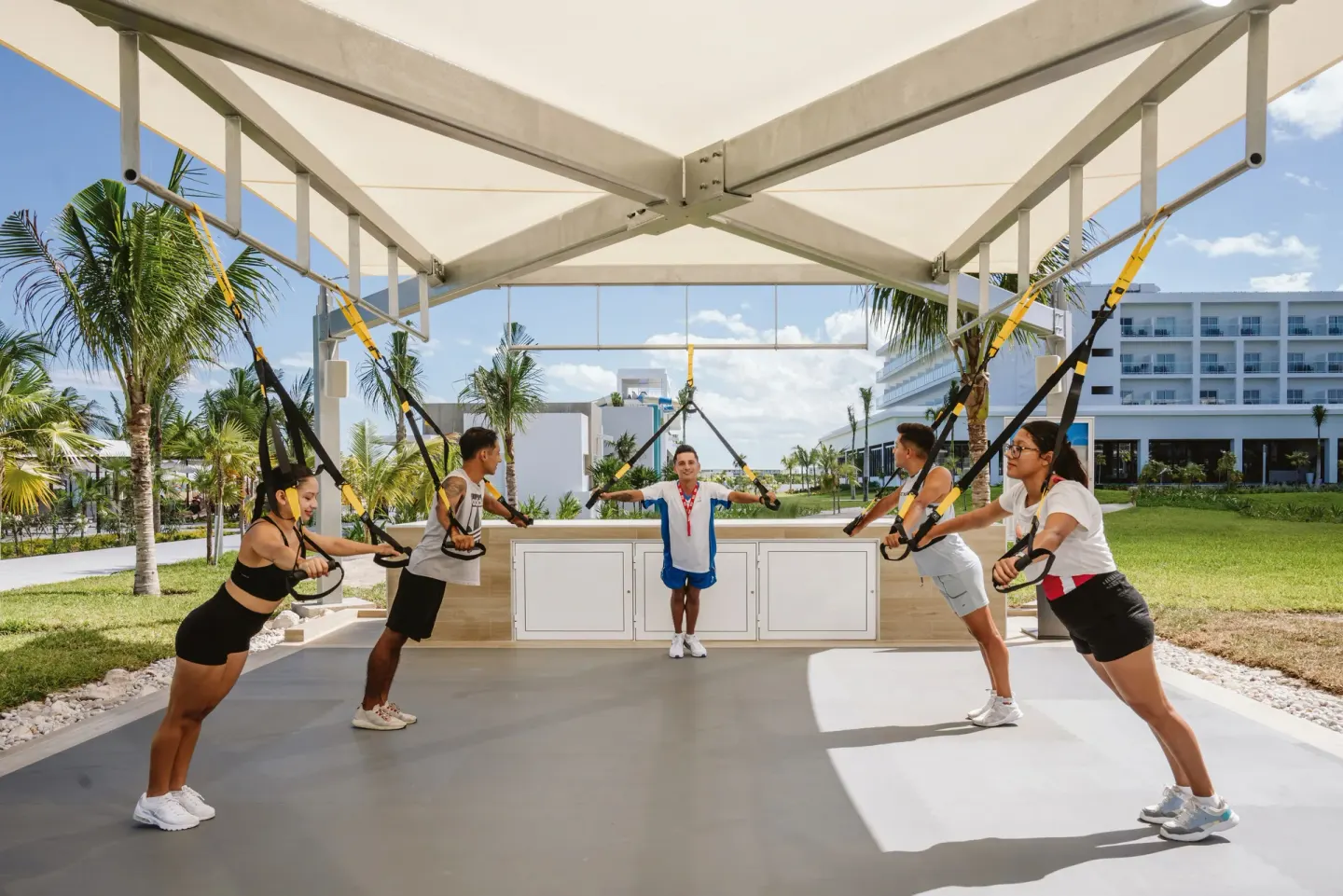 Suspension strap fitness class under a canopy at Hotel Riu Latino.
