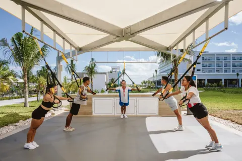 Suspension strap fitness class under a canopy at Hotel Riu Latino.