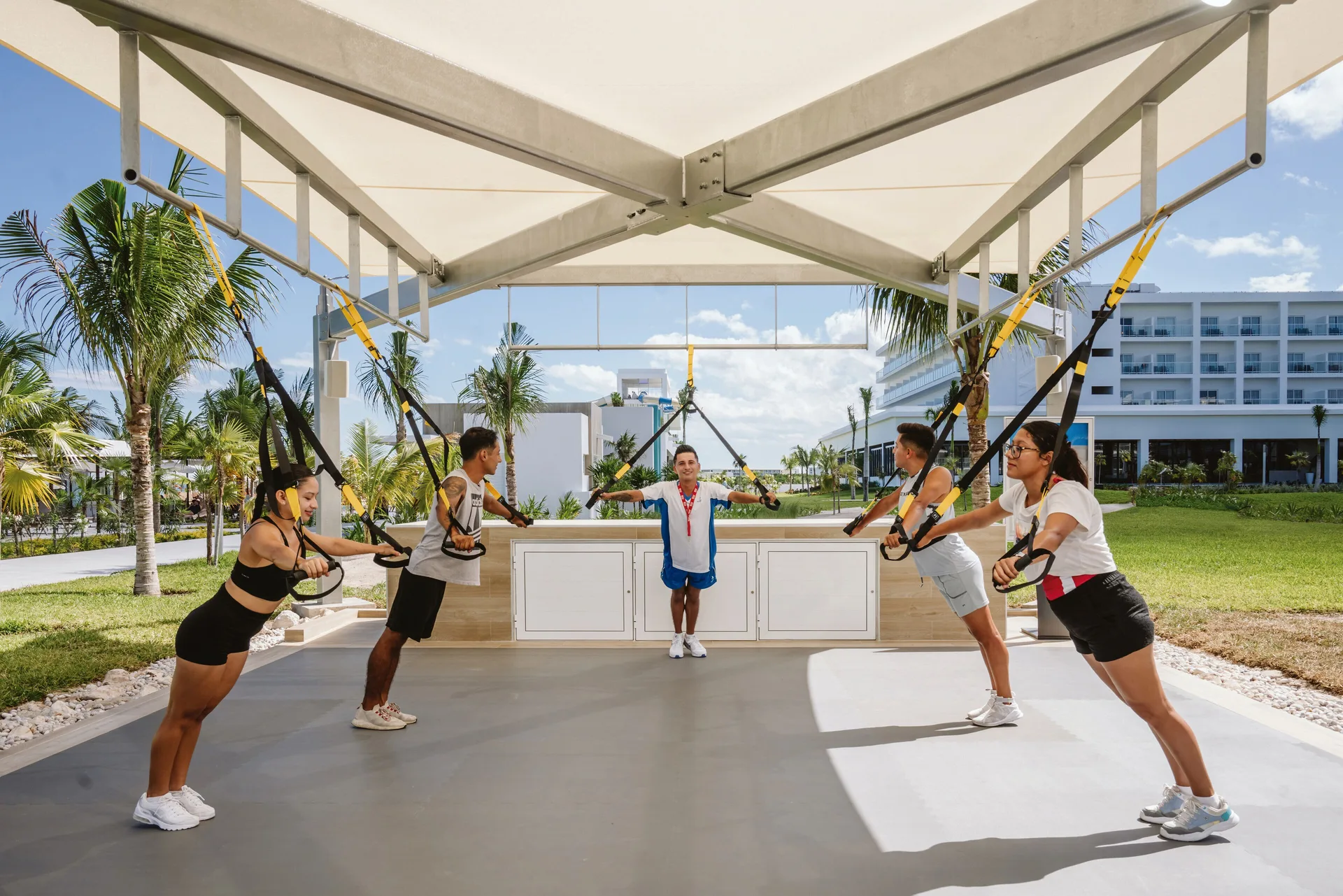 Suspension strap fitness class under a canopy at Hotel Riu Latino.