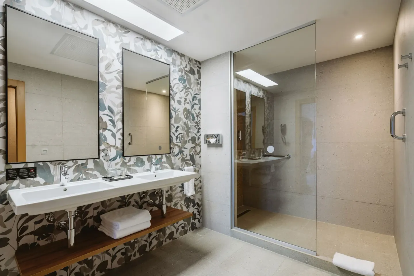 Guest room bathroom with double sinks and glass shower at Hotel Riu Latino.