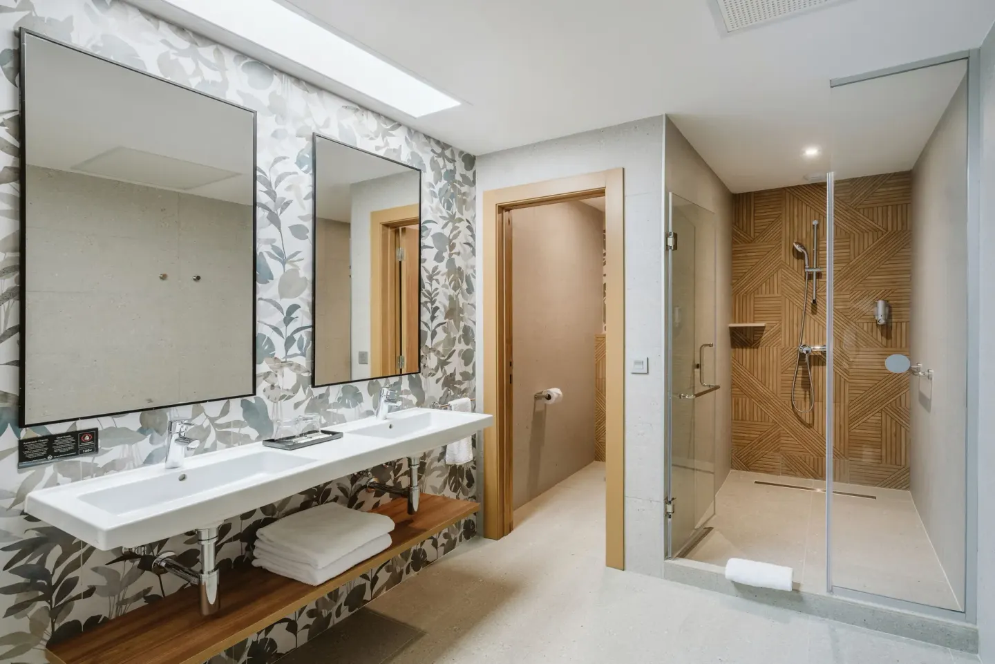 Guest room bathroom with double vanity, toilet room, and walk-in shower at Hotel Riu Latino.
