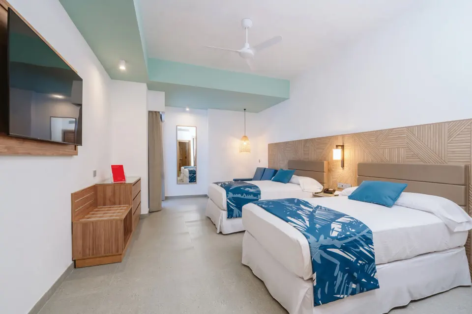 Guest room with two beds and wall-mounted TV at Hotel Riu Latino.