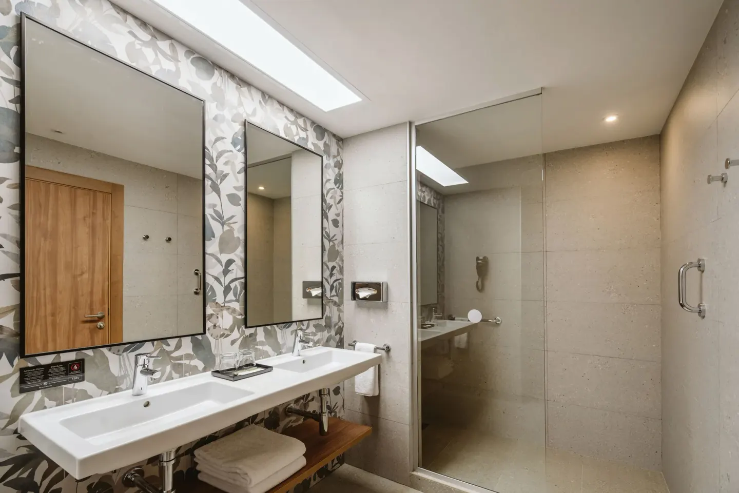 Partial Ocean View room bathroom with double sink and glass shower at Hotel Riu Latino.