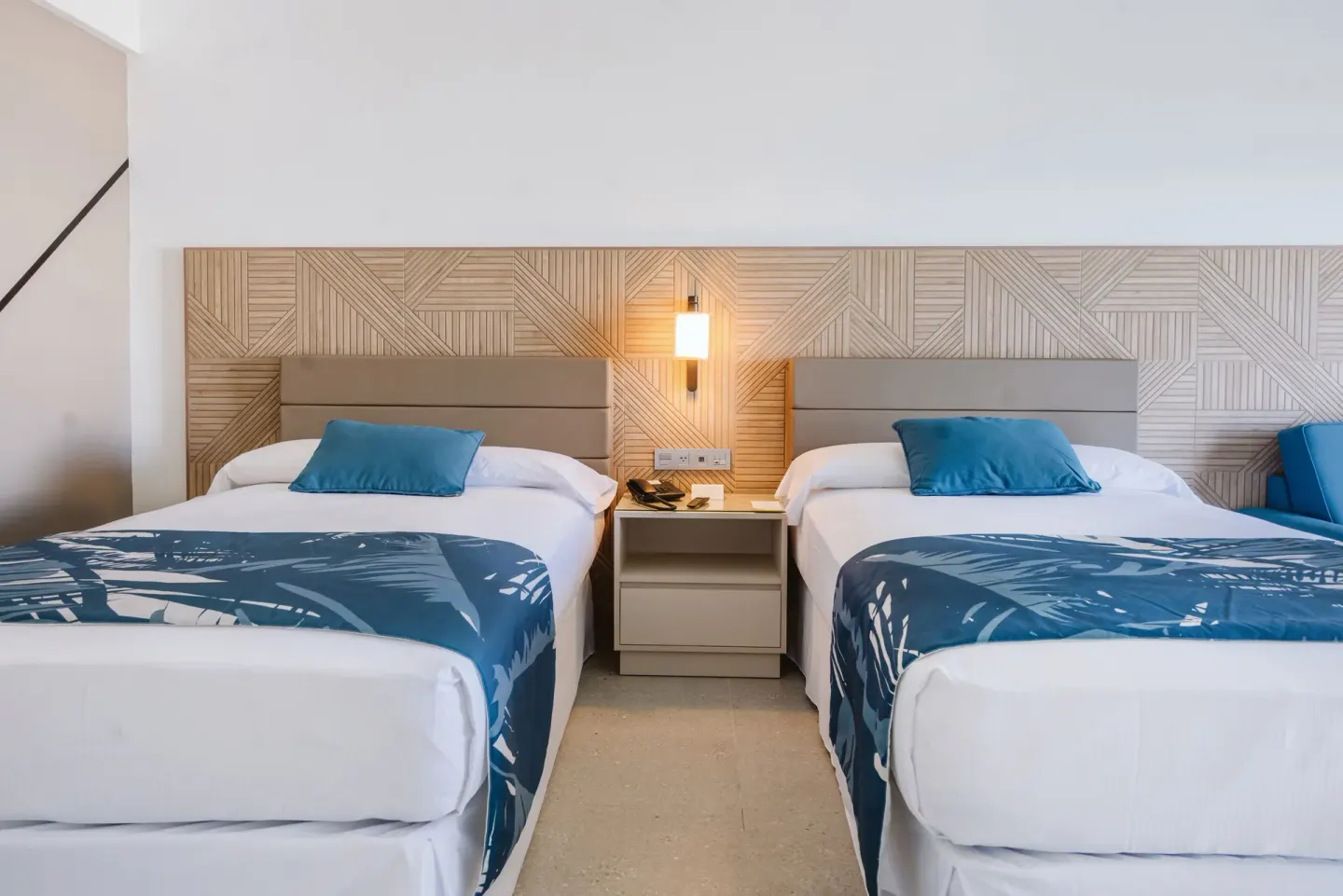 Partial Ocean View room with two beds and blue bed runners at Hotel Riu Latino.