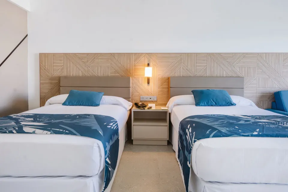 Partial Ocean View room with two beds and blue bed runners at Hotel Riu Latino.