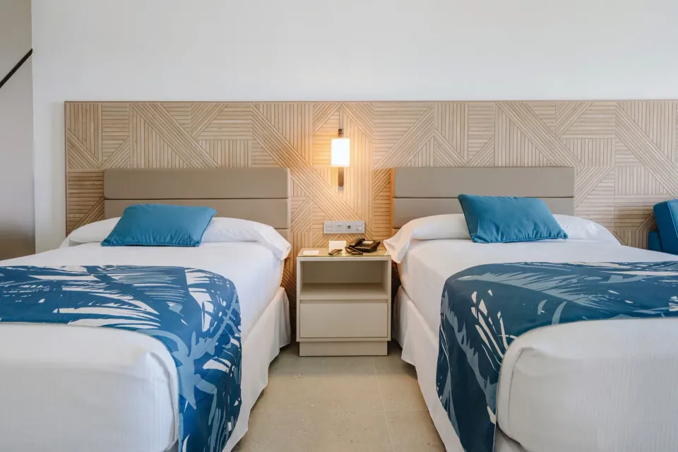 Standard Room with two beds, blue runners, and patterned headboard at Hotel Riu Latino.