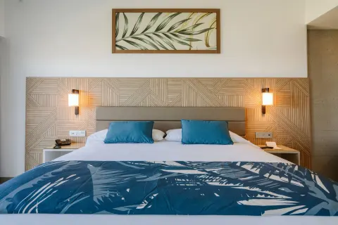 King bed in an Ocean View Suite at Hotel Riu Latino with wood headboard and blue accents.