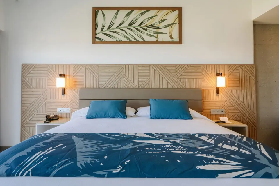 King bed in an Ocean View Suite at Hotel Riu Latino with wood headboard and blue accents.
