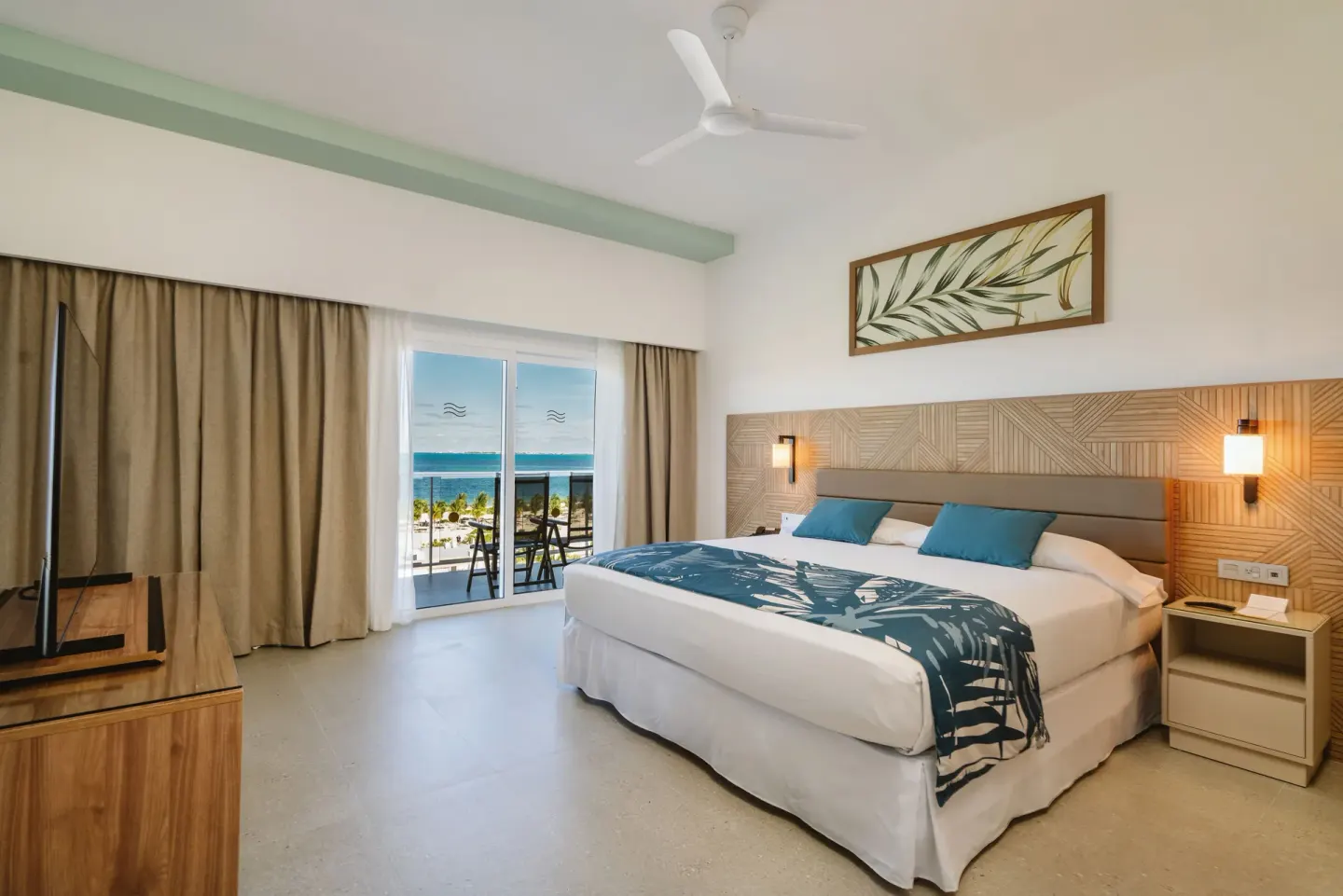 Ocean View Suite at Hotel Riu Latino with king bed, TV cabinet, balcony, and sea beyond.