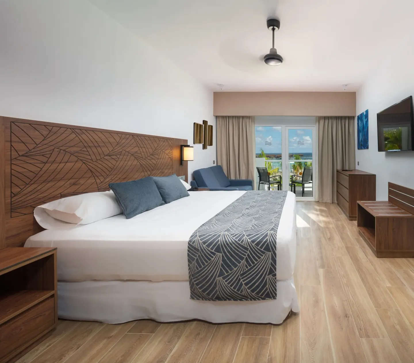 Guest room at Hotel Riu Montego Bay with a king bed, sofa, balcony and ocean glimpse.