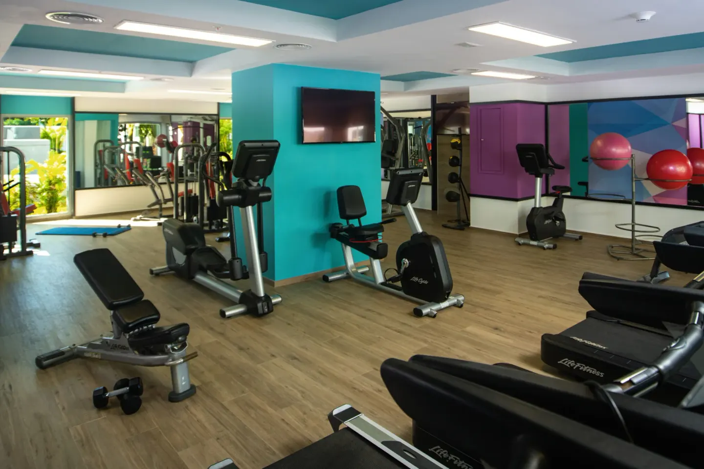 Indoor fitness room with cardio machines and weights at Hotel Riu Montego Bay.