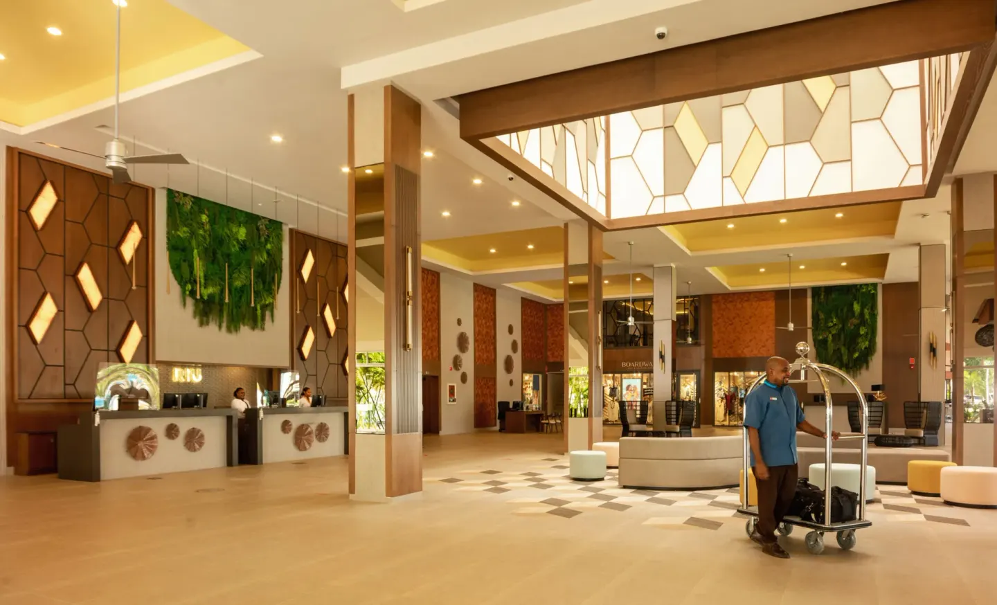 Bright lobby at Hotel Riu Montego Bay with reception desks, seating and a luggage cart.