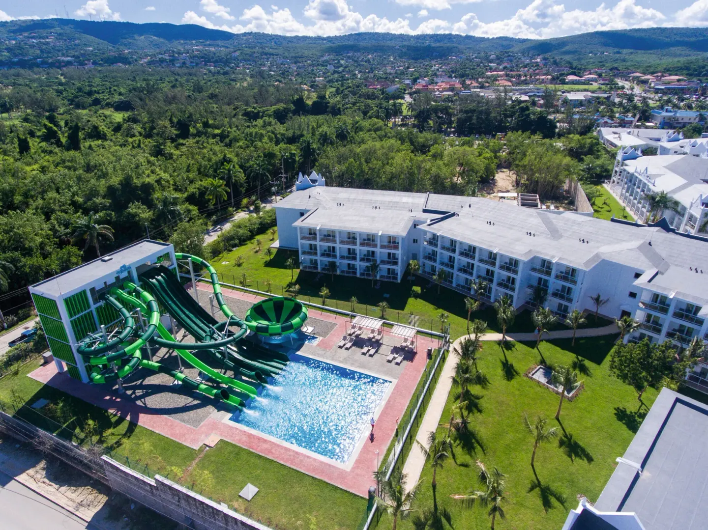 Aerial view of green water slides, pool, and resort buildings at Hotel Riu Montego Bay.