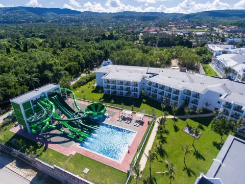 Aerial view of green water slides, pool, and resort buildings at Hotel Riu Montego Bay.