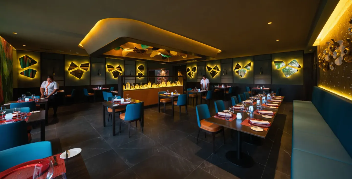 Stylish restaurant dining room with teal seating and warm wall lighting at Hotel Riu Montego Bay.