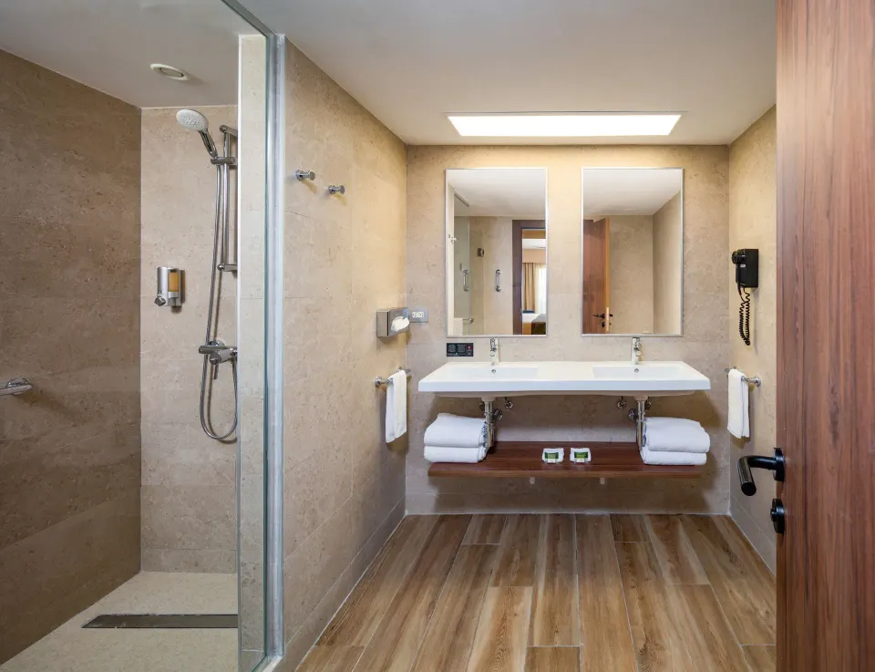 Guest bathroom with double sink vanity and glass shower at Hotel Riu Montego Bay.