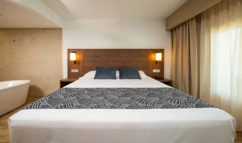 Suite Ocean View king bed with patterned headboard and curtains at Hotel Riu Montego Bay.