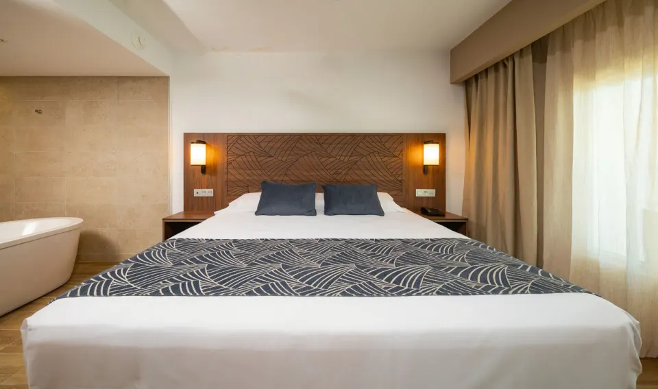 Suite Ocean View king bed with patterned headboard and curtains at Hotel Riu Montego Bay.