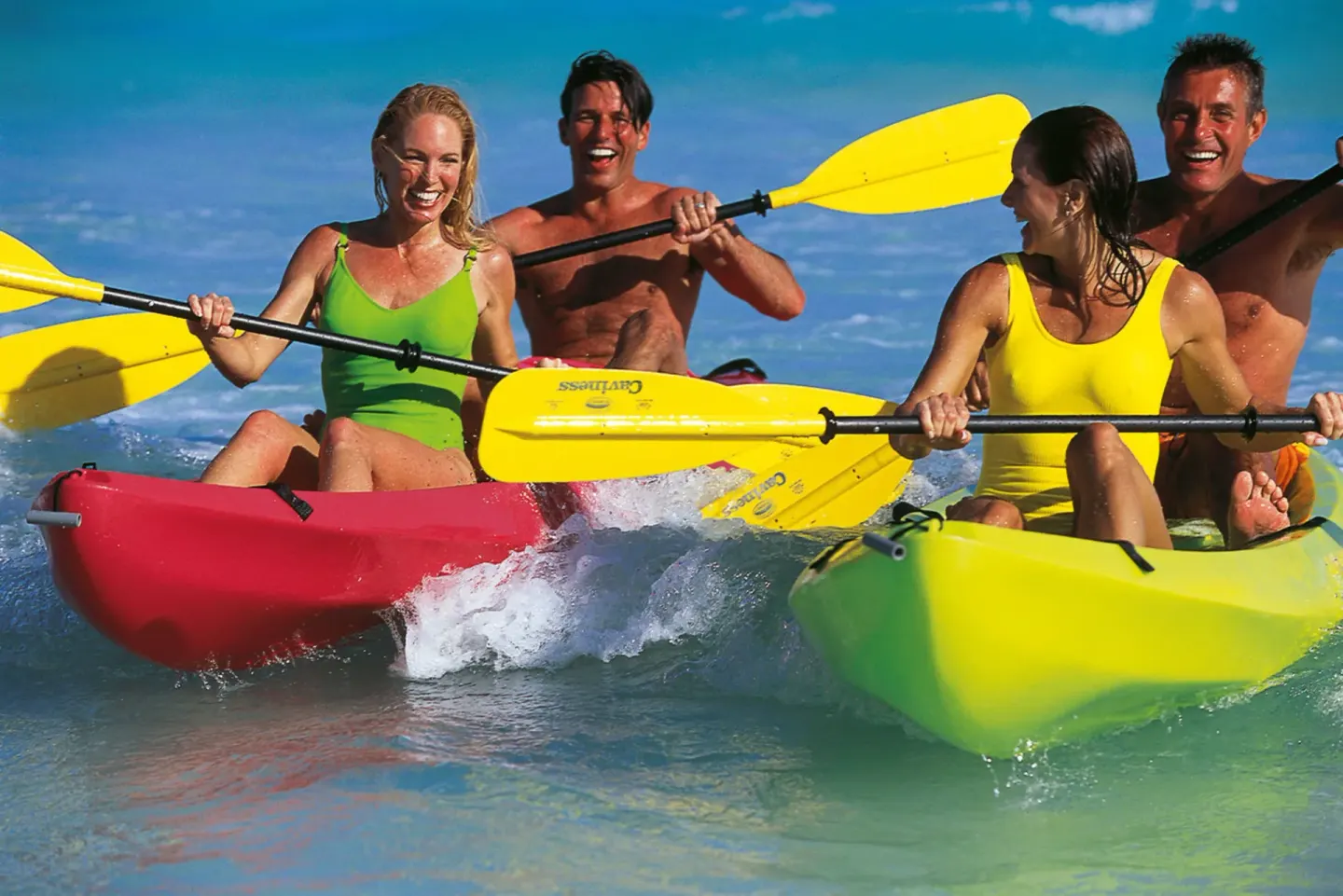 Guests paddle colorful kayaks in shallow turquoise water at Hotel Riu Ocho Rios.