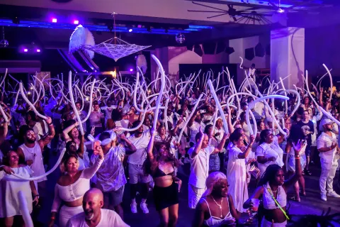 A large crowd waves long balloons during a party at Hotel Riu Ocho Rios.