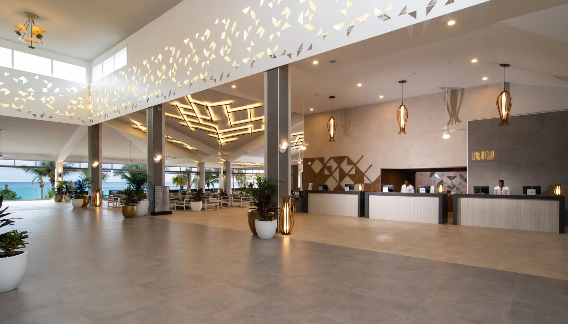 Open lobby with reception desks and ocean glimpses at Hotel Riu Ocho Rios.