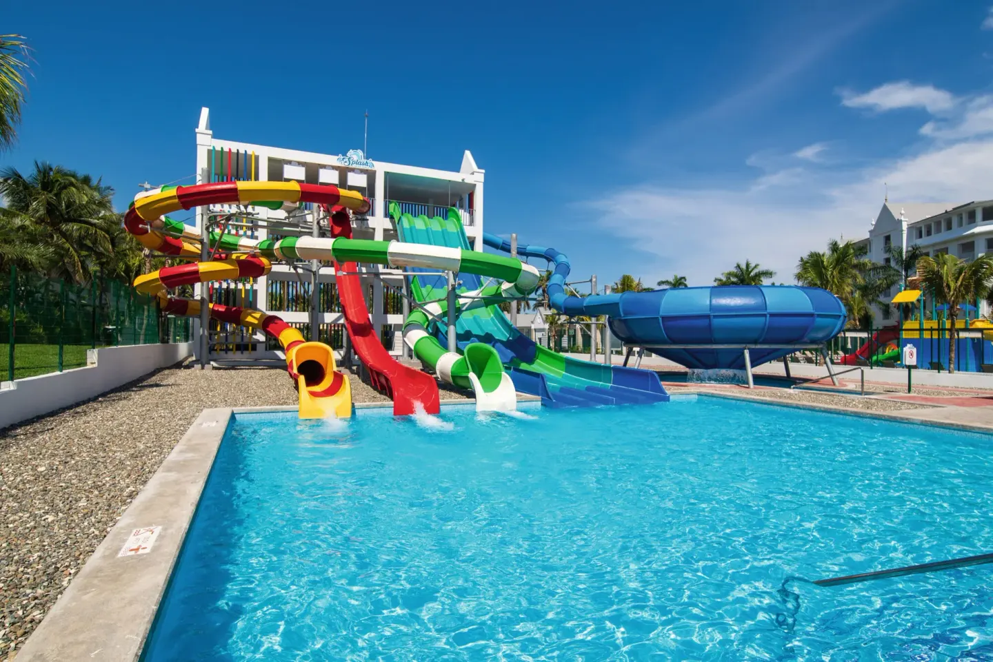 Water park pool with colorful tube slides and a large blue bowl slide at Hotel Riu Ocho Rios.