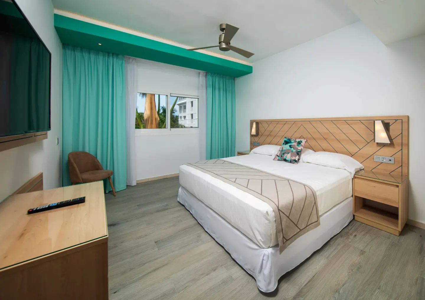 King bed bedroom with wall-mounted TV in a Family Room at Hotel Riu Ocho Rios.