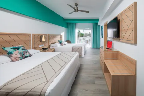 Family Room bedroom with two double beds, TV, and balcony doors at Hotel Riu Ocho Rios.