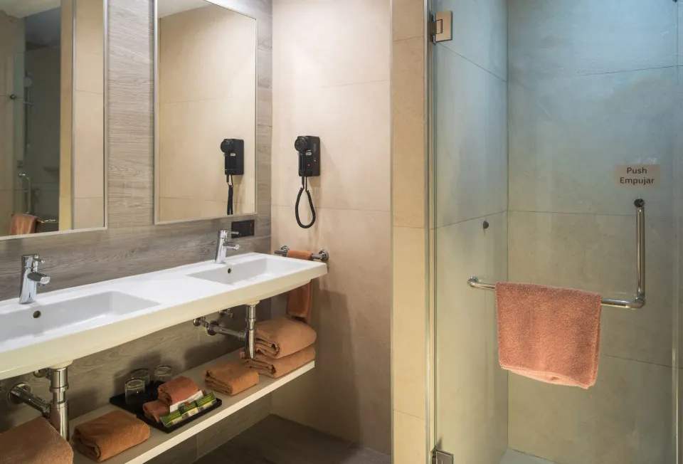 Family Room bathroom with double sink vanity and glass shower at Hotel Riu Ocho Rios.
