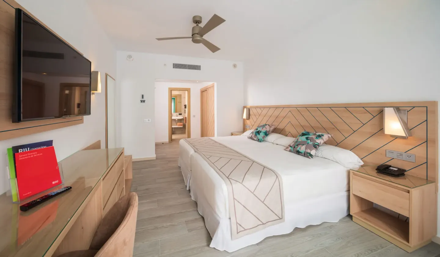Ocean View room with a large bed, wall-mounted TV, and wood furniture at Hotel Riu Ocho Rios.