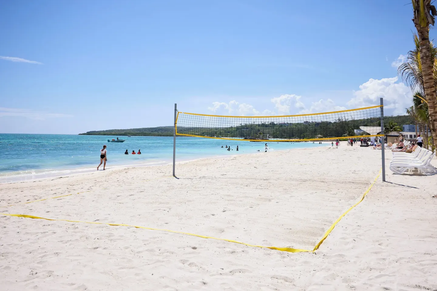 Beach volleyball court at Hotel Riu Palace Aquarelle set on white sand beside turquoise water.