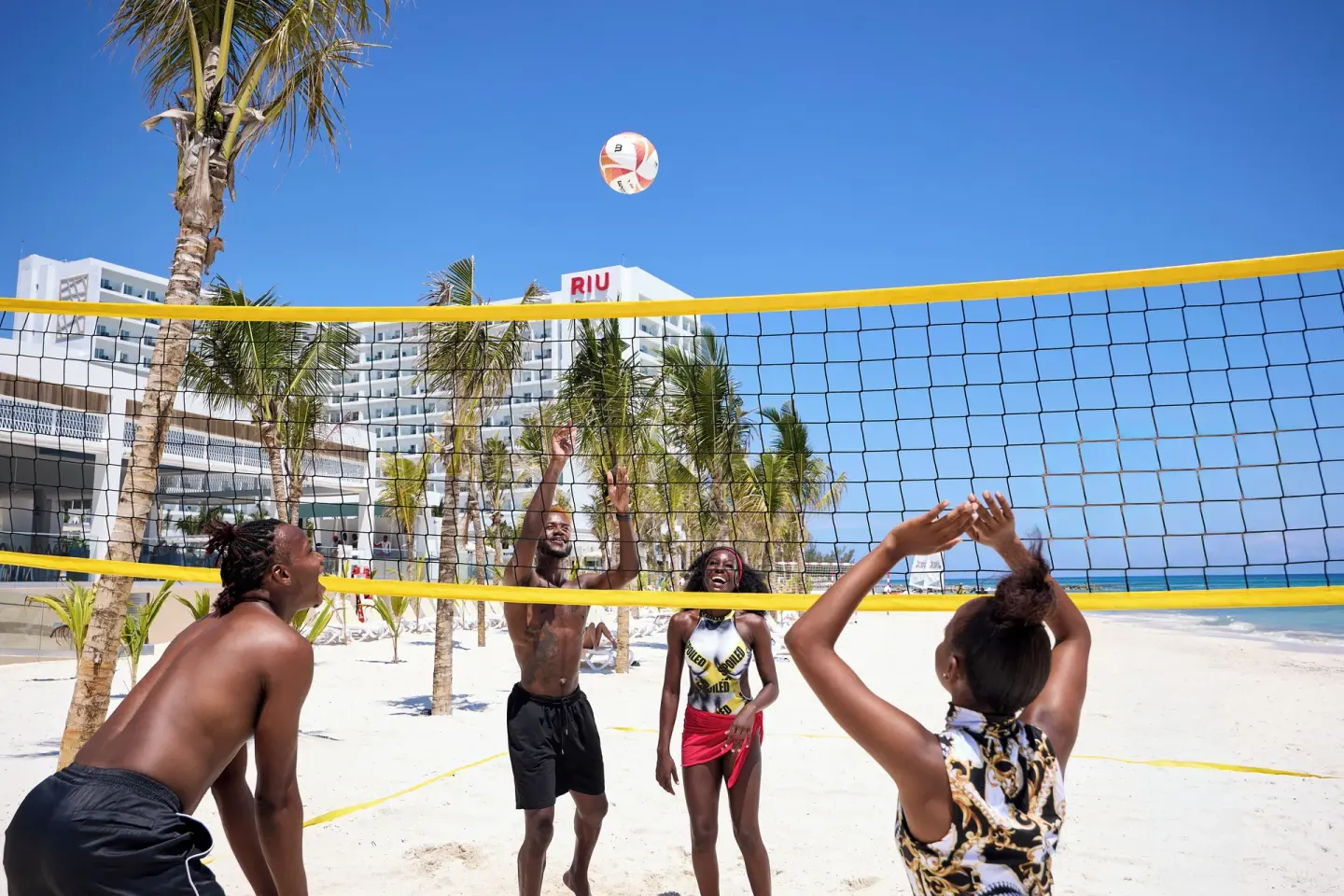Guests playing beach volleyball beside Hotel Riu Palace Aquarelle.