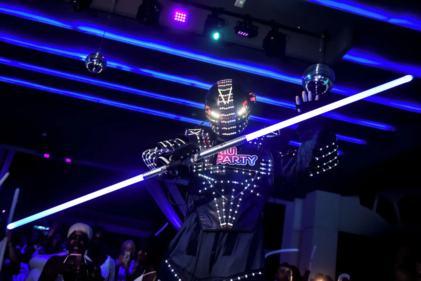 A costumed performer holds a glowing staff during a party at Hotel Riu Palace Aquarelle.