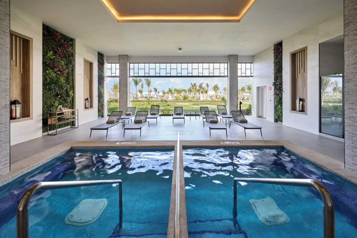 Indoor spa pools with loungers and garden views at Hotel Riu Palace Aquarelle.