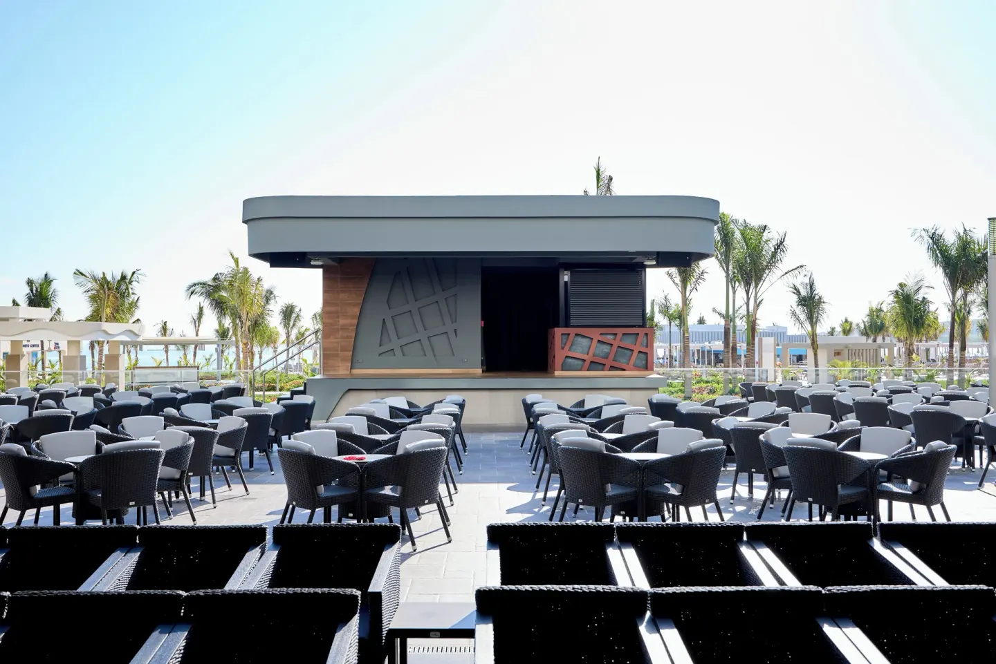 Rows of patio chairs face an outdoor stage at Hotel Riu Palace Aquarelle.