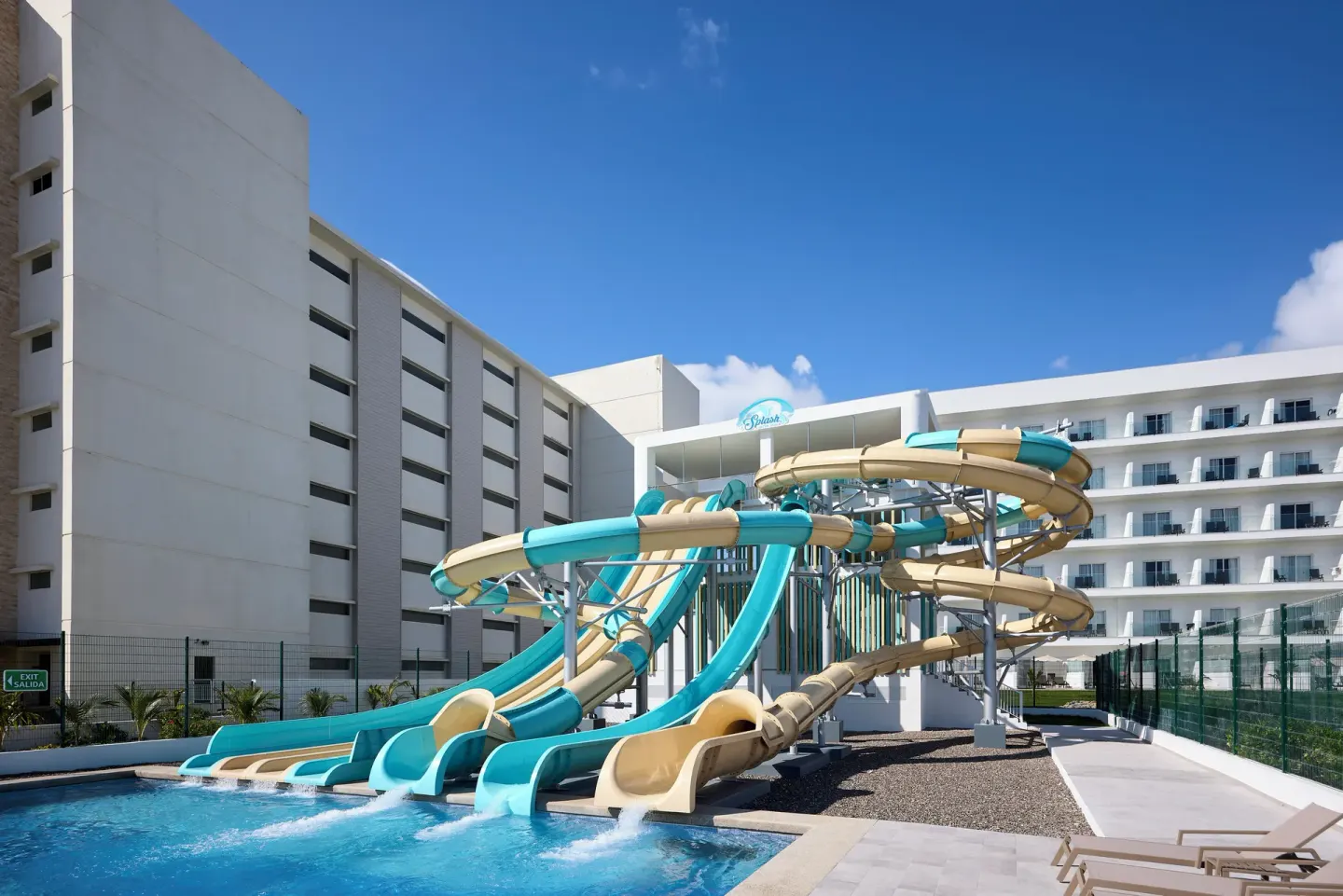 Aqua and beige water slides empty into a pool at Hotel Riu Palace Aquarelle.
