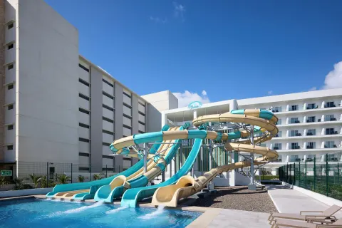 Aqua and beige water slides empty into a pool at Hotel Riu Palace Aquarelle.