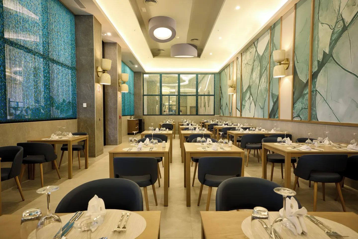 Modern dining room with blue seating and wall art at Hotel Riu Palace Aquarelle.