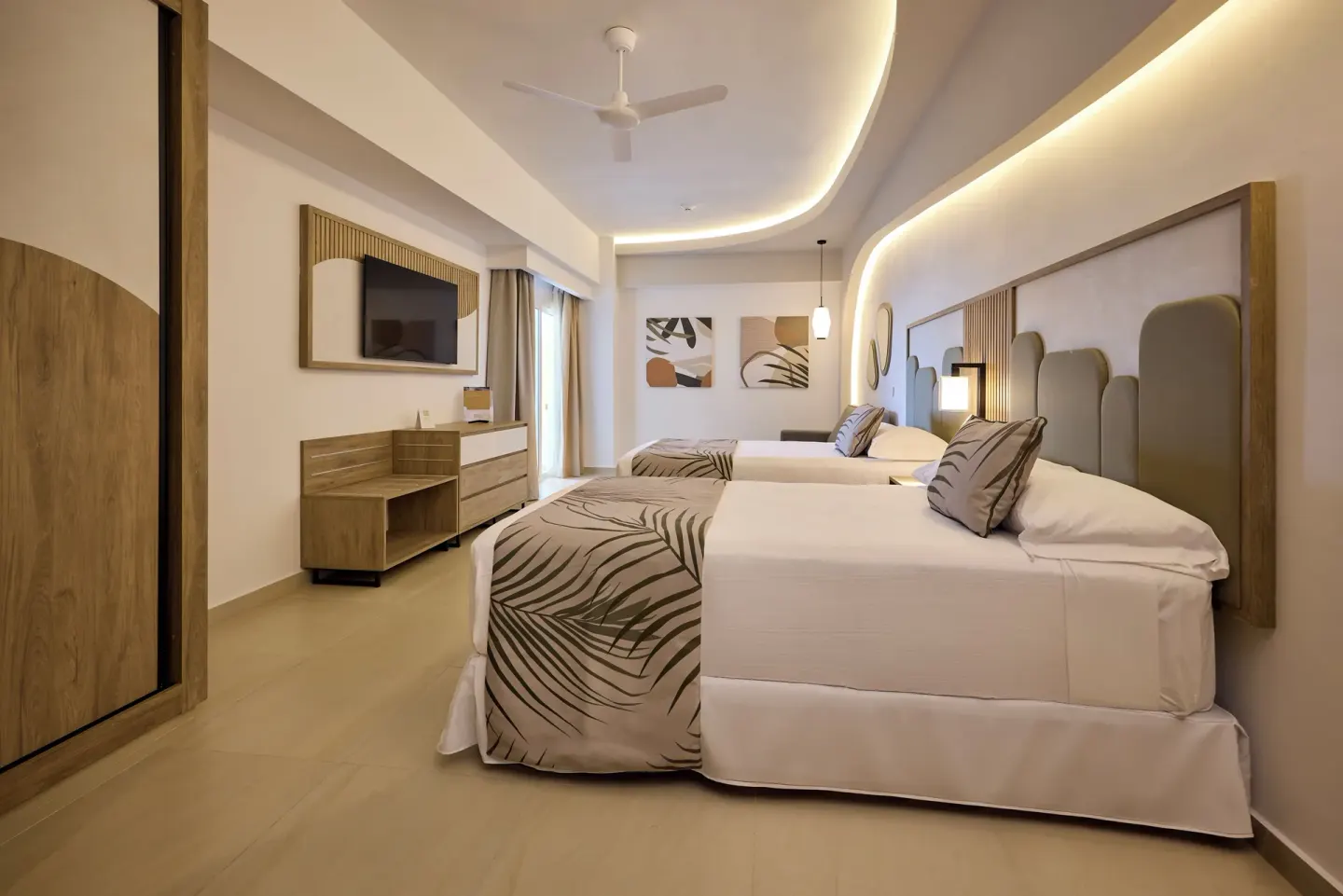 Family Room with multiple beds and TV area at Hotel Riu Palace Aquarelle.