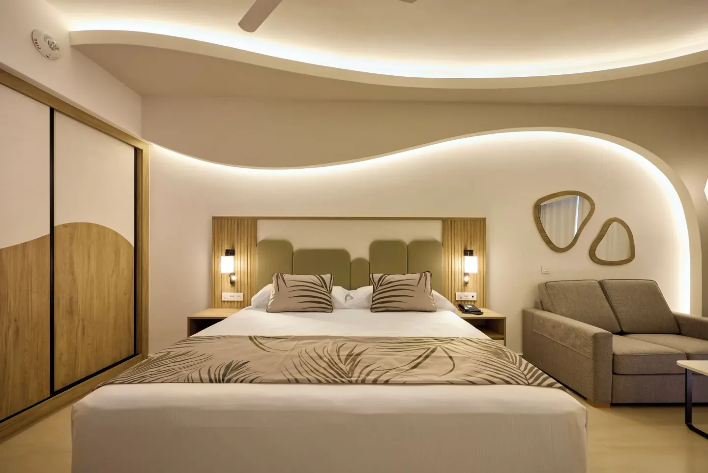 Oceanfront Junior Suite bedroom with king bed and sofa at Hotel Riu Palace Aquarelle.