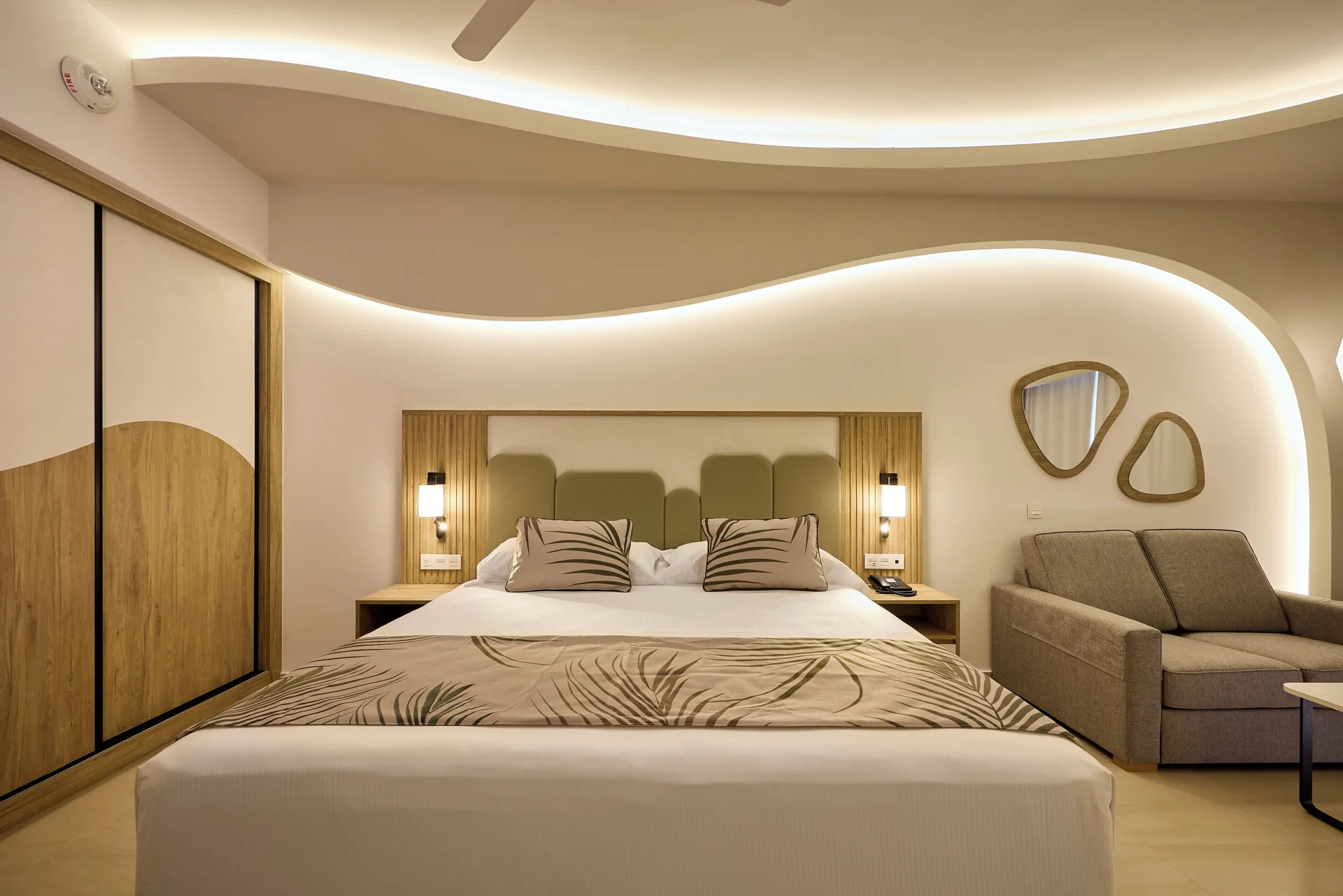 Oceanfront Junior Suite bedroom with king bed and sofa at Hotel Riu Palace Aquarelle.