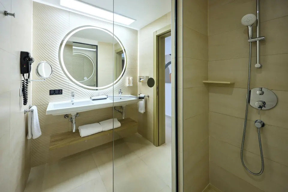 Junior Suite Partial Ocean View bathroom with vanity and shower at Hotel Riu Palace Aquarelle.