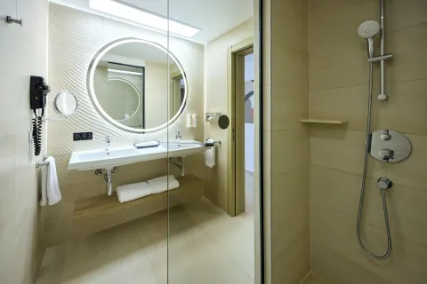 Ocean Front Junior Suite bathroom with lit mirror and glass shower at Hotel Riu Palace Aquarelle.