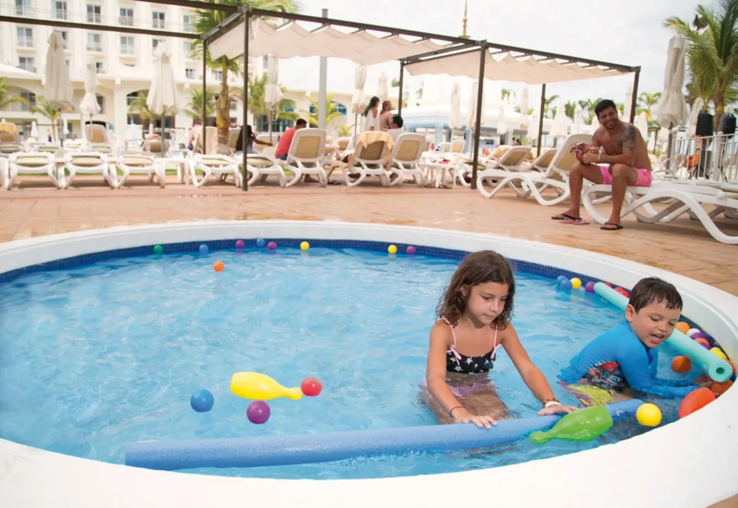 Children play with pool toys in the kids' pool at Hotel Riu Palace Aruba.