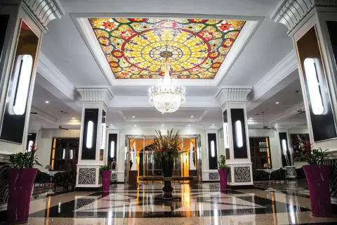 Lobby ceiling with stained-glass panel and chandelier at Hotel Riu Palace Aruba.