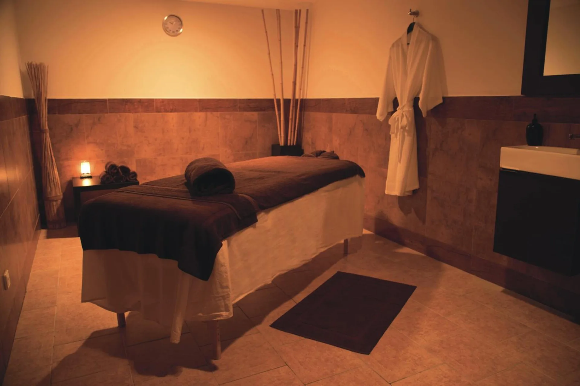 A warm-lit massage room with treatment bed at Hotel Riu Palace Aruba.
