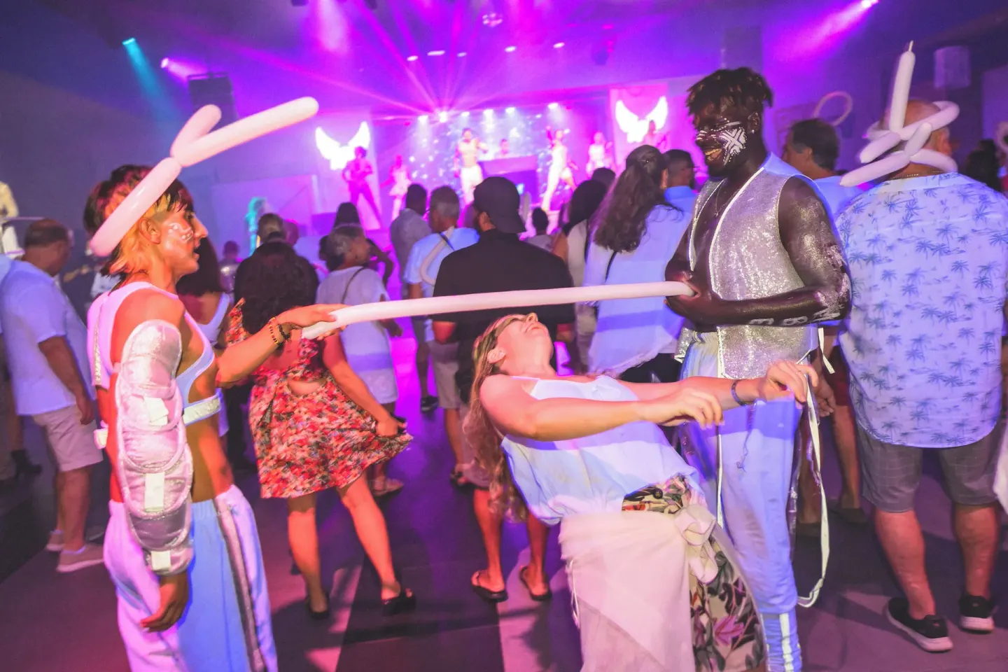 Guests dance with entertainers during a neon party at Hotel Riu Palace Aruba.