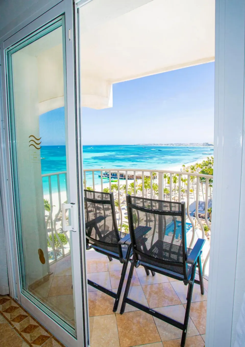 Balcony chairs overlooking turquoise water and Palm Beach at Hotel Riu Palace Aruba.