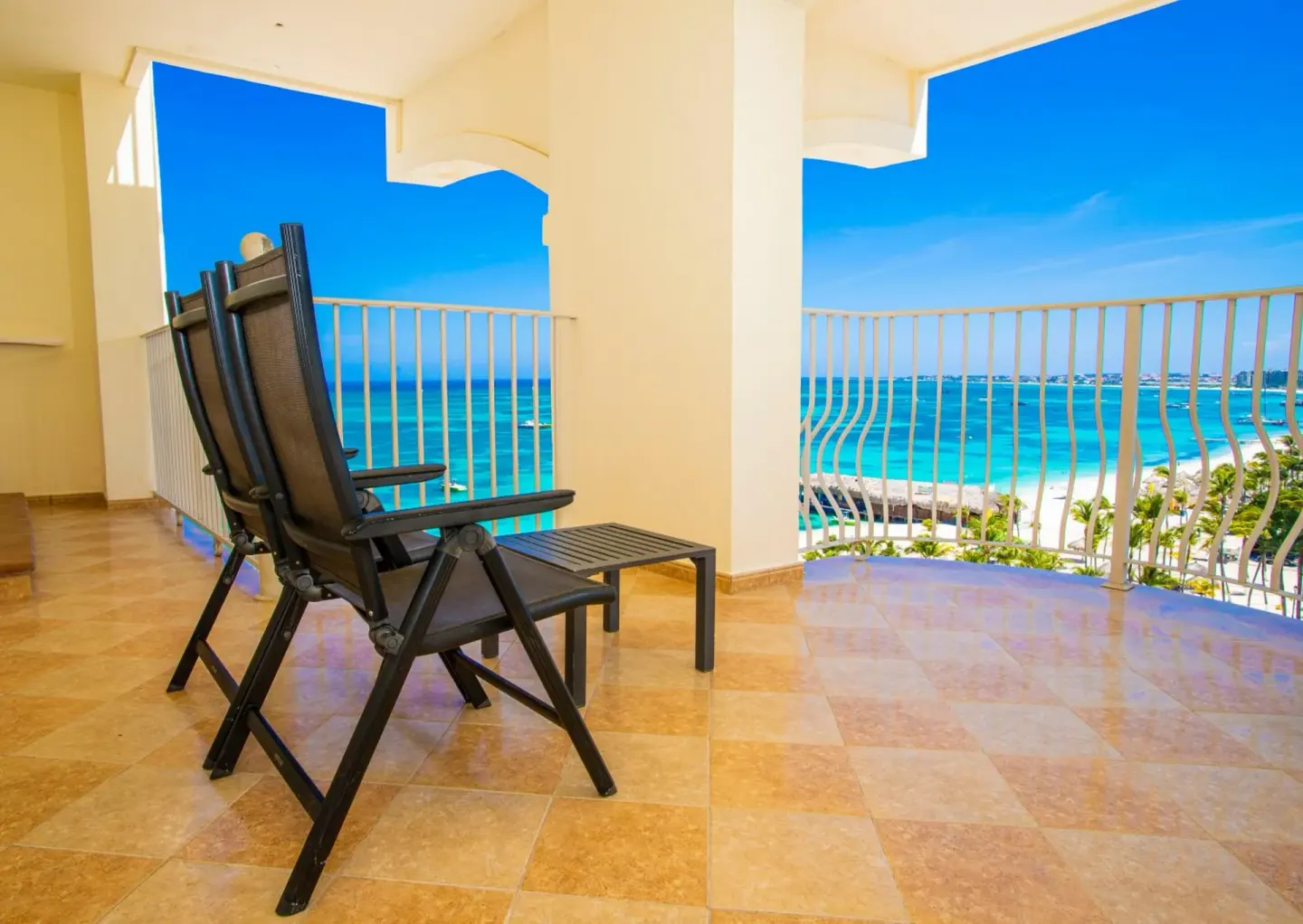 Balcony seating overlooks turquoise ocean water at Hotel Riu Palace Aruba.