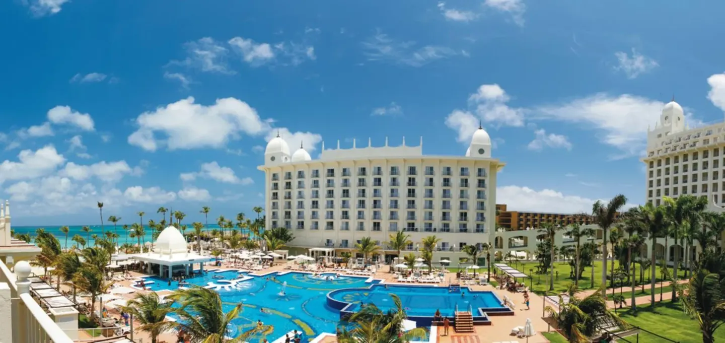 Aerial view of the pool, towers, palms and ocean at Hotel Riu Palace Aruba.